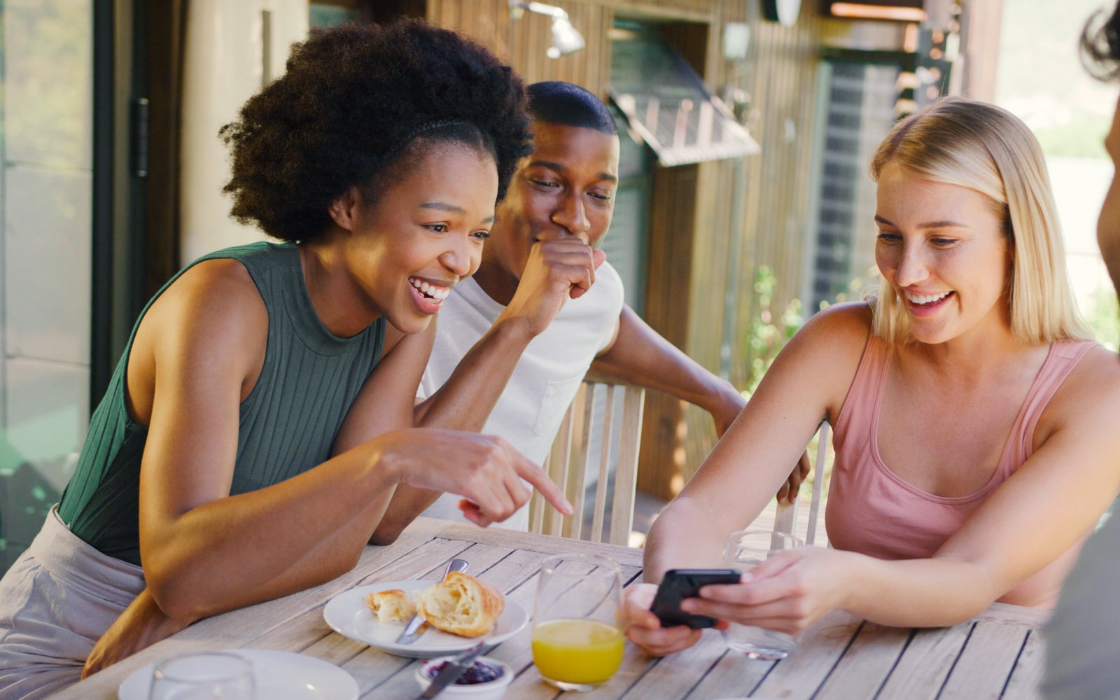 Friends at a restaurant table ordering and paying together from a smartphone