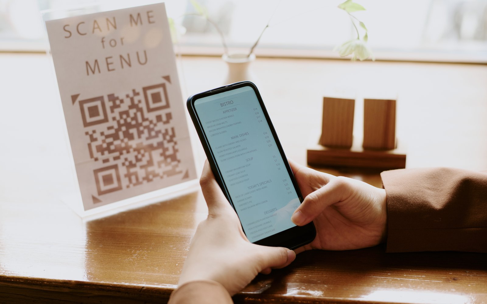 Guest scanning a QR code menu at a restaurant table to order and pay from their phone